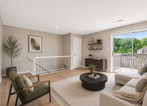 A living room with a white couch, a coffee table, and a tree.