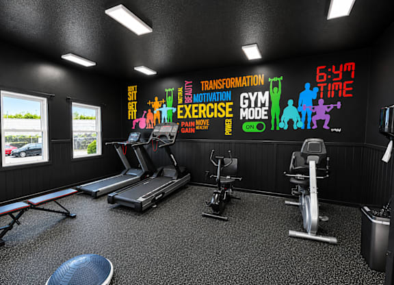 A gym with a variety of equipment and motivational wall decals.