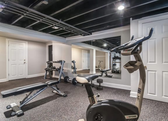 A home gym with a variety of equipment including a treadmill, weights, and a bench press.