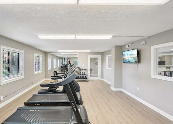 A gym with treadmills and a television on the wall.