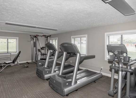 A room with a treadmill, elliptical trainer and a stationary bike.