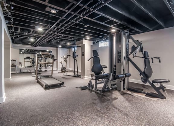 A spacious gym with a variety of equipment including a leg press machine, a chest press machine, and a bench press.