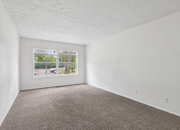 Empty room with carpeted floor and a window.