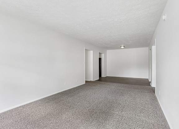 A long, empty hallway with carpeted floors and white walls.
