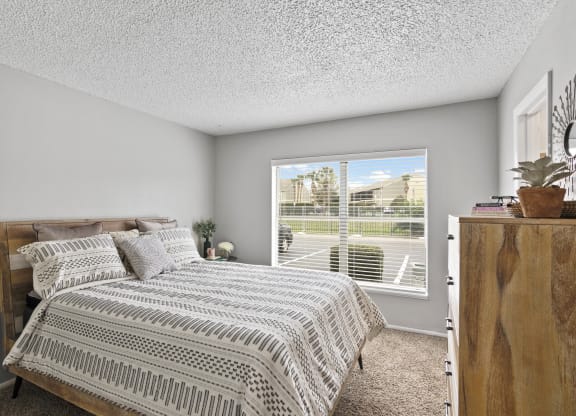 an empty bedroom with a bed and a large window