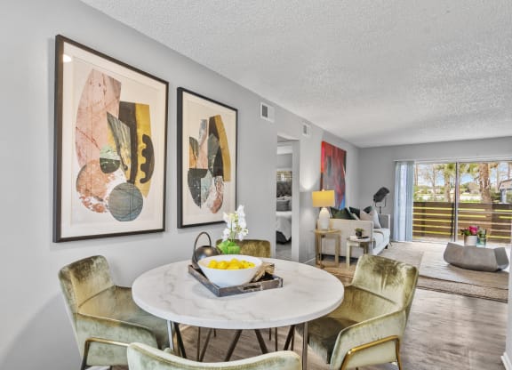 a living room with a table and chairs and paintings on the wall