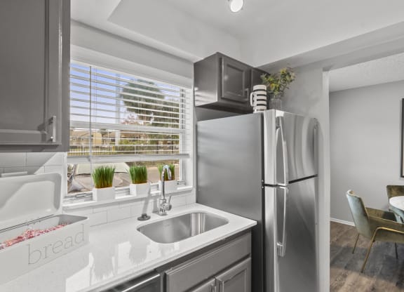 a kitchen with stainless steel refrigerator and sink and a window