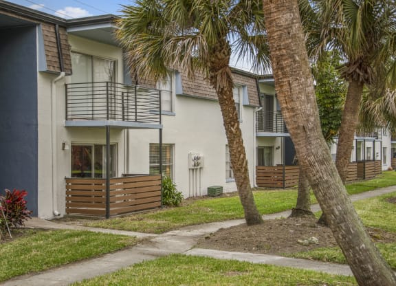 a sidewalk in front of a building with palm trees