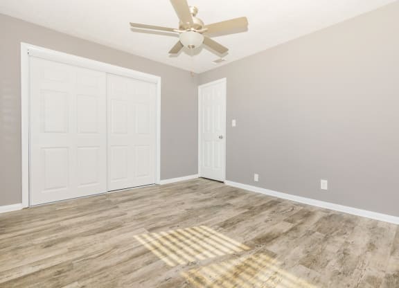 an empty room with a ceiling fan and a closet