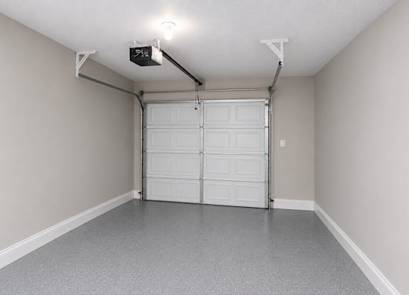 A garage with a white door and a grey floor.