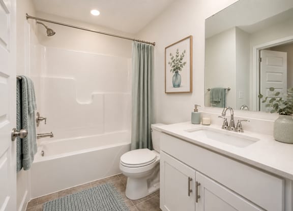 A white bathroom with a toilet, sink, and shower.