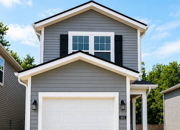 A house with a grey and white exterior and a white garage door.