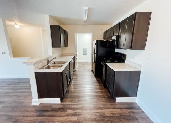 an empty kitchen with black appliances and wooden floors