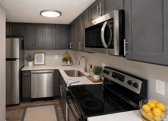 A modern kitchen with a stove, microwave, and refrigerator.