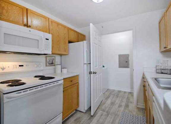A kitchen with white appliances and wooden cabinets.