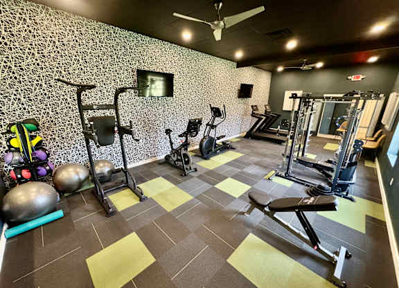 A gym with a variety of equipment including weights and a bench press. at Townhomes at 28th, Columbus, IN