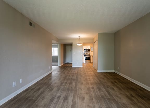 A long, empty hallway with wood flooring and white walls.