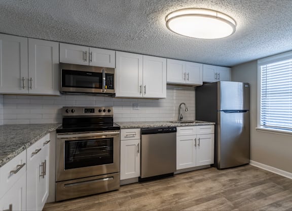 A kitchen with stainless steel appliances and white cabinets.