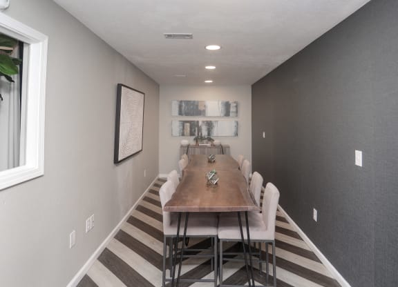 a dining room with a long wooden table and white chairs
