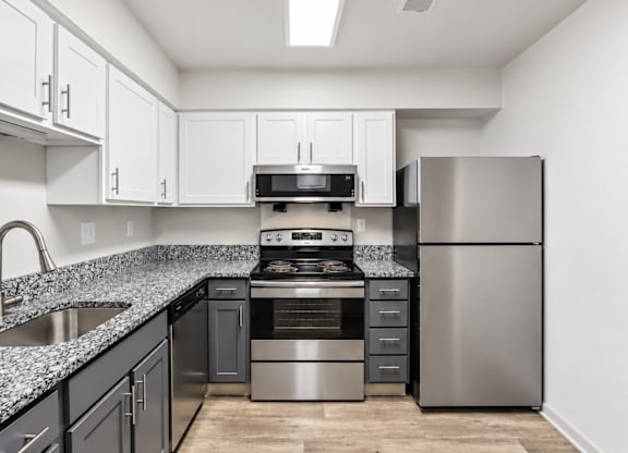 A kitchen with a stainless steel refrigerator and a black and white counter.