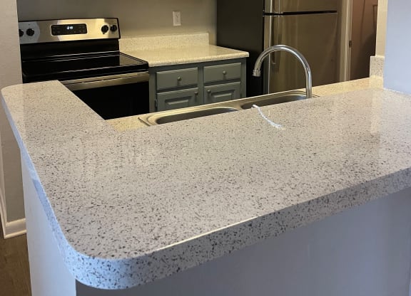 a kitchen with granite counter tops and stainless steel appliances at Aqua Bay Apartments in Naples, FL 34116
