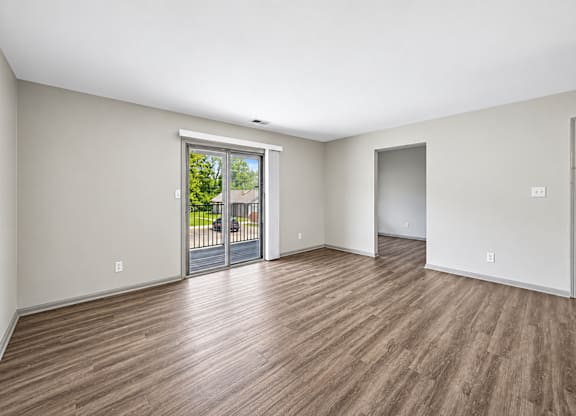 A room with wooden flooring and a sliding glass door leading to a balcony.