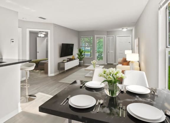 A dining room table with plates and a vase of flowers on top of it at Aqua Bay Apartments in Naples, FL 34116