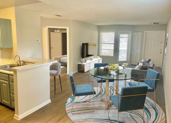 a living room and kitchen with a glass table and chairs at Aqua Bay Apartments in Naples, FL 34116