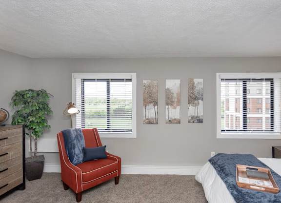 A bedroom with a red chair and a bed with a blue blanket.