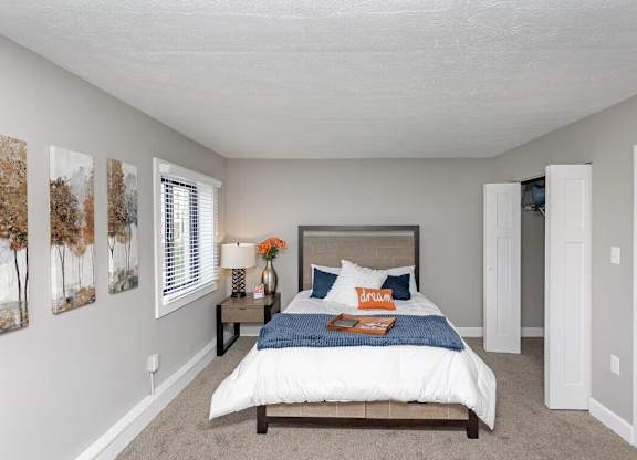 A bedroom with a bed, nightstand, and two framed pictures on the wall.
