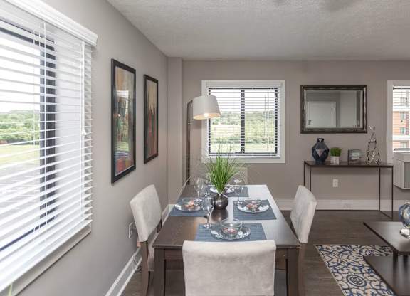 A dining room with a table set for two and a view of the backyard.