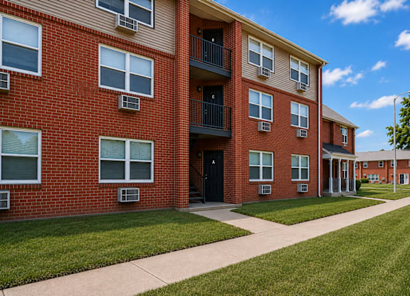 A red brick apartment building with a balcony on the second floor.