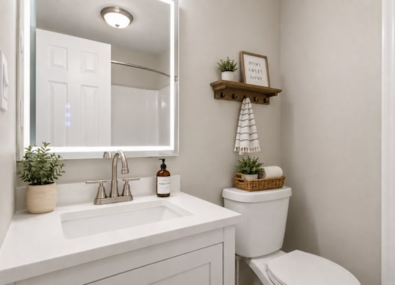 A bathroom with a toilet, sink, and a mirror.
