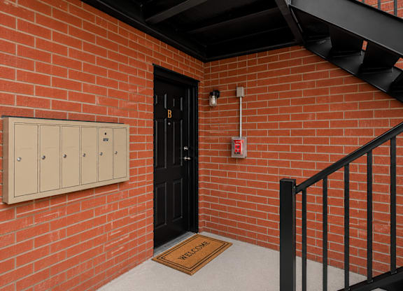 A red brick wall with a black door and a black railing.