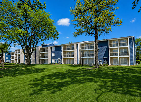 A large grassy area in front of a building with trees on either side.