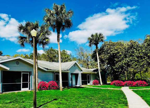 A blue house with palm trees in front of it at Aqua Bay Apartments in Naples, FL 34116