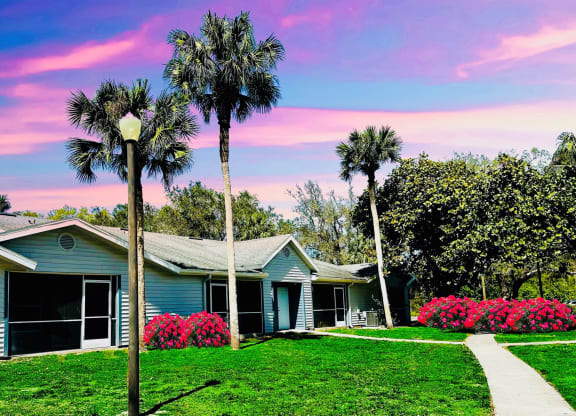 A blue house with palm trees in front of it at Aqua Bay Apartments in Naples, FL 34116