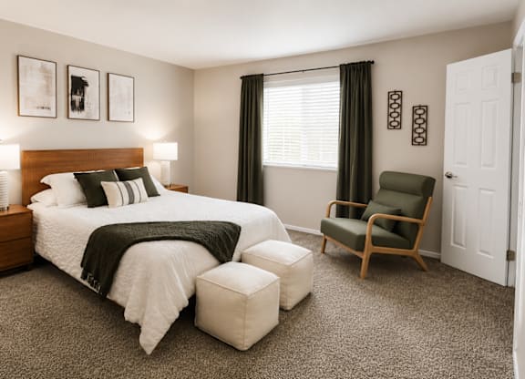 A bedroom with a bed, chair, and nightstand.