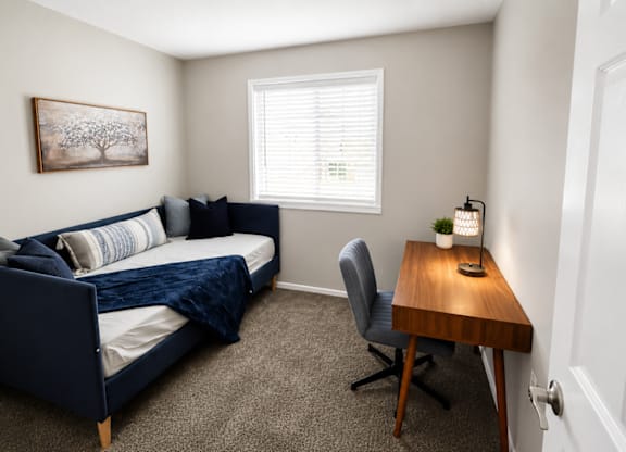 A bedroom with a bed, chair, and a painting on the wall.