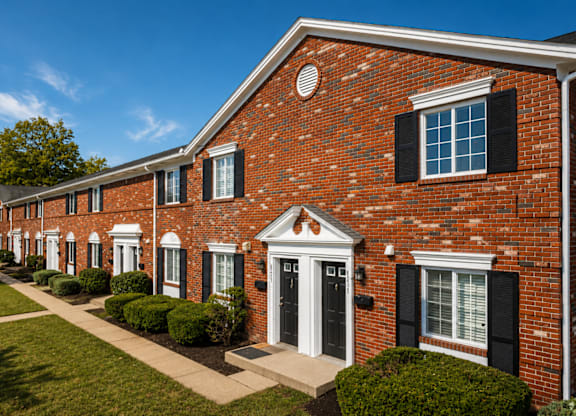A row of red brick houses with black shutters and white trim.
