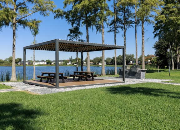 a pavilion with benches in a park next to a lake