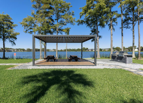 a picnic pavilion in a park next to a lake