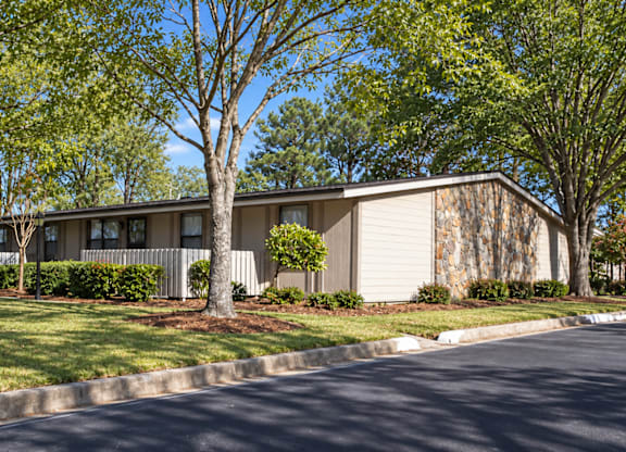 A building with a grey facade is surrounded by green trees.