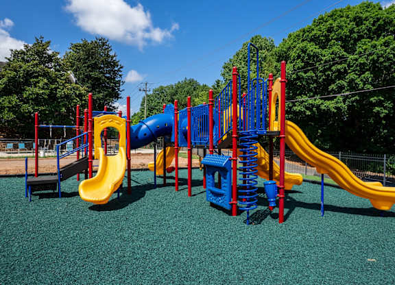 A playground with a blue and yellow slide and a red and blue climbing frame.