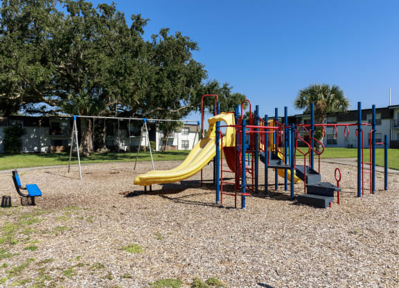 a playground with a yellow slide in a park