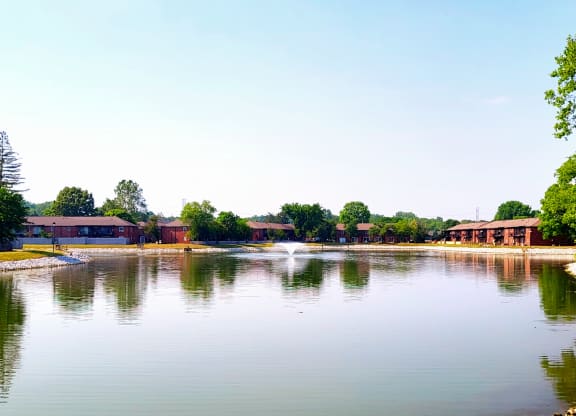 a fountain in the middle of a lake with buildings in the background