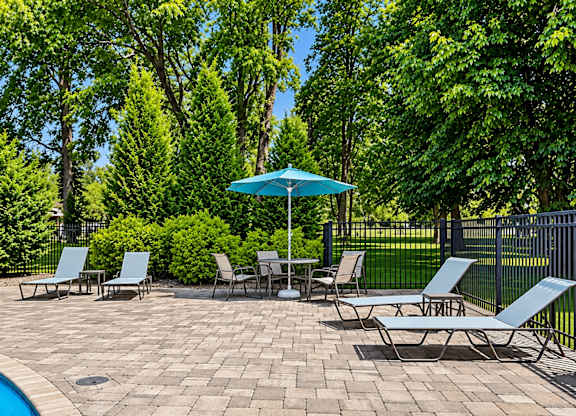 A patio with chairs and a table with a blue umbrella.