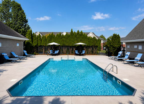 A large swimming pool surrounded by lounge chairs and umbrellas.