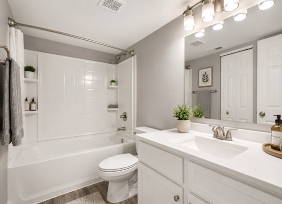 A white bathroom with a toilet, sink, and mirror.