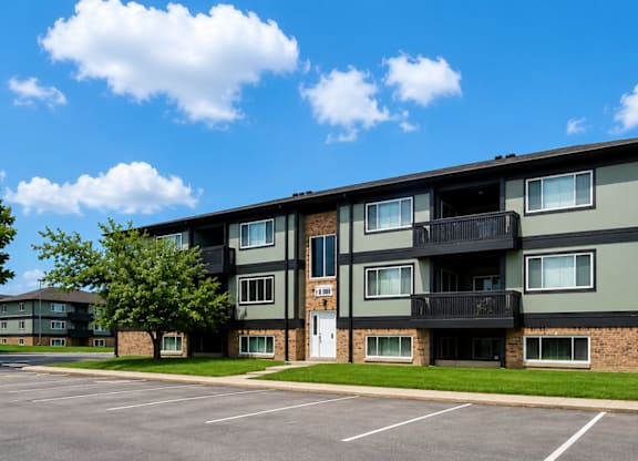 A large apartment building with a parking lot in front.